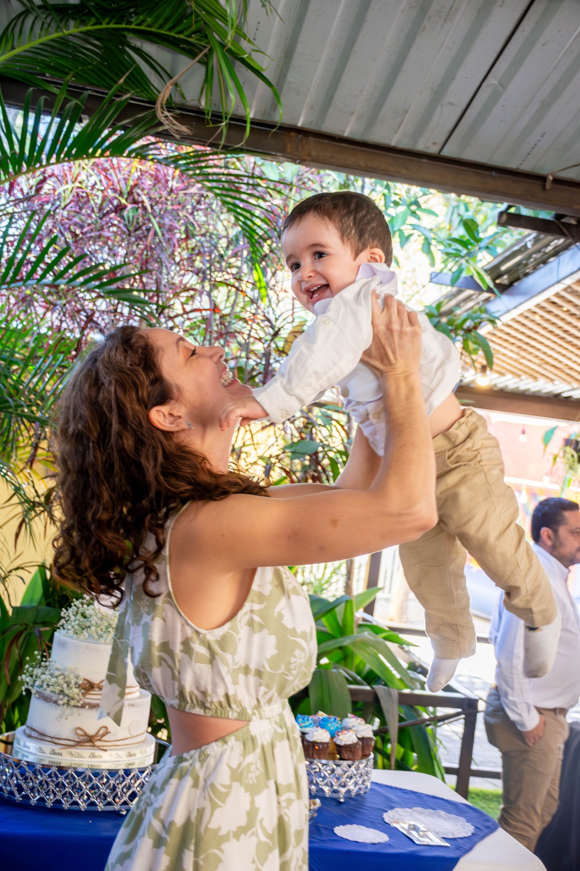 Mamá levantando a su bebé y sonriendo en un jardín